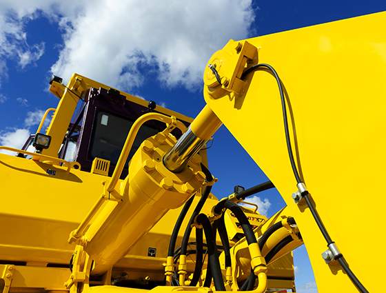 Bulldozer, huge yellow powerful construction machinery with big bucket, focused on hydraulic piston arm, blue sky and white clouds on background